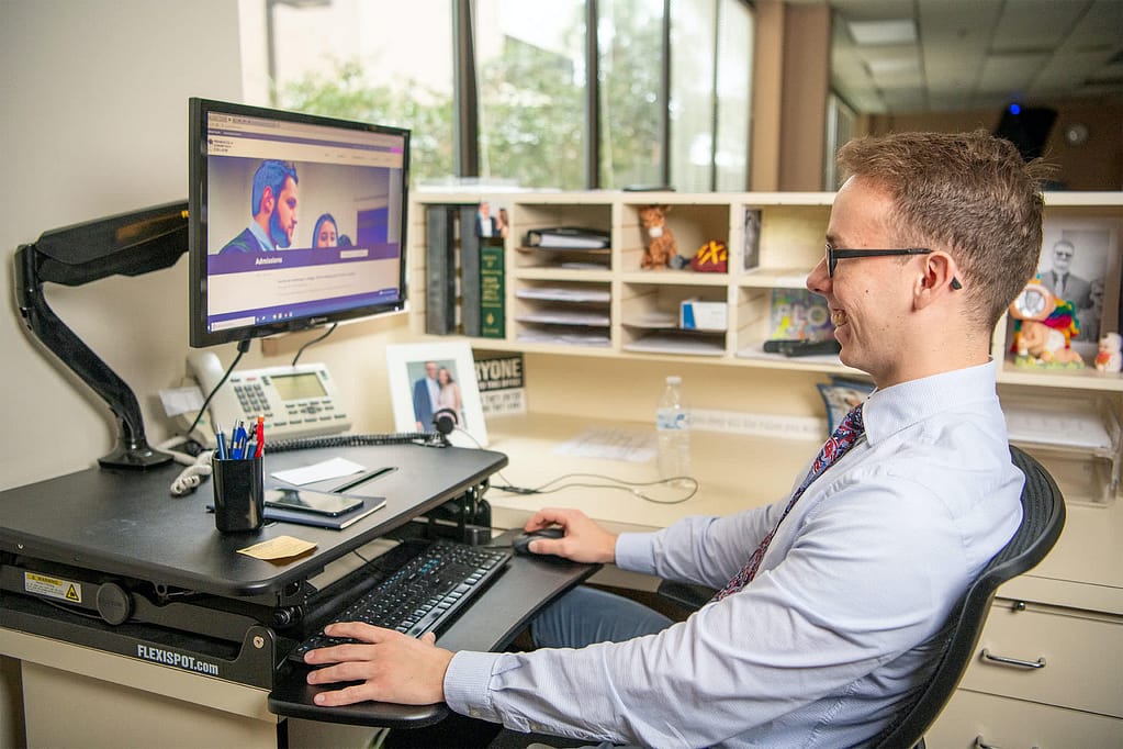 Admissions advisor working on a computer. 