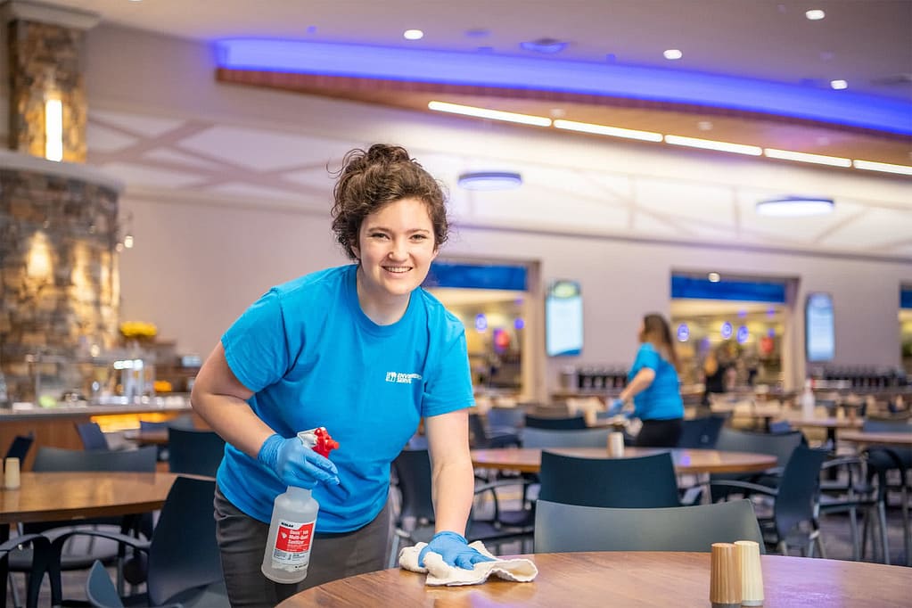 Environmental Service student worker cleans the varsity tables.