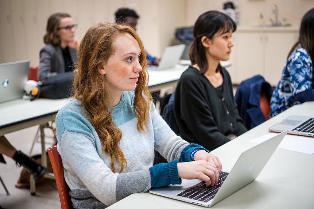 Graduate Assistants sitting at desks with laptops. 