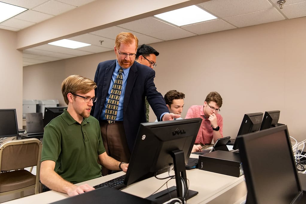 Mike Geary helping a student at a computer.