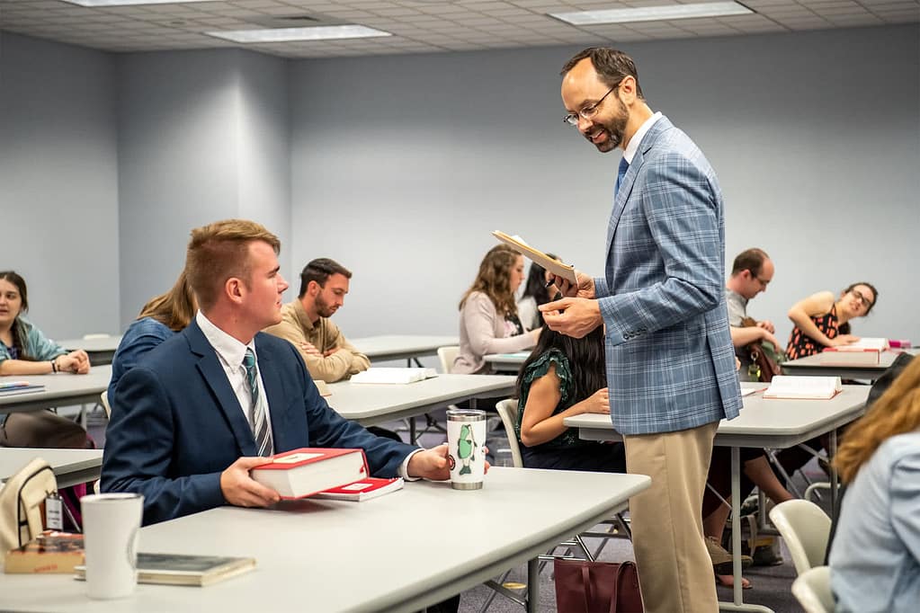 Dr. Achuff talking to a student at their desk.