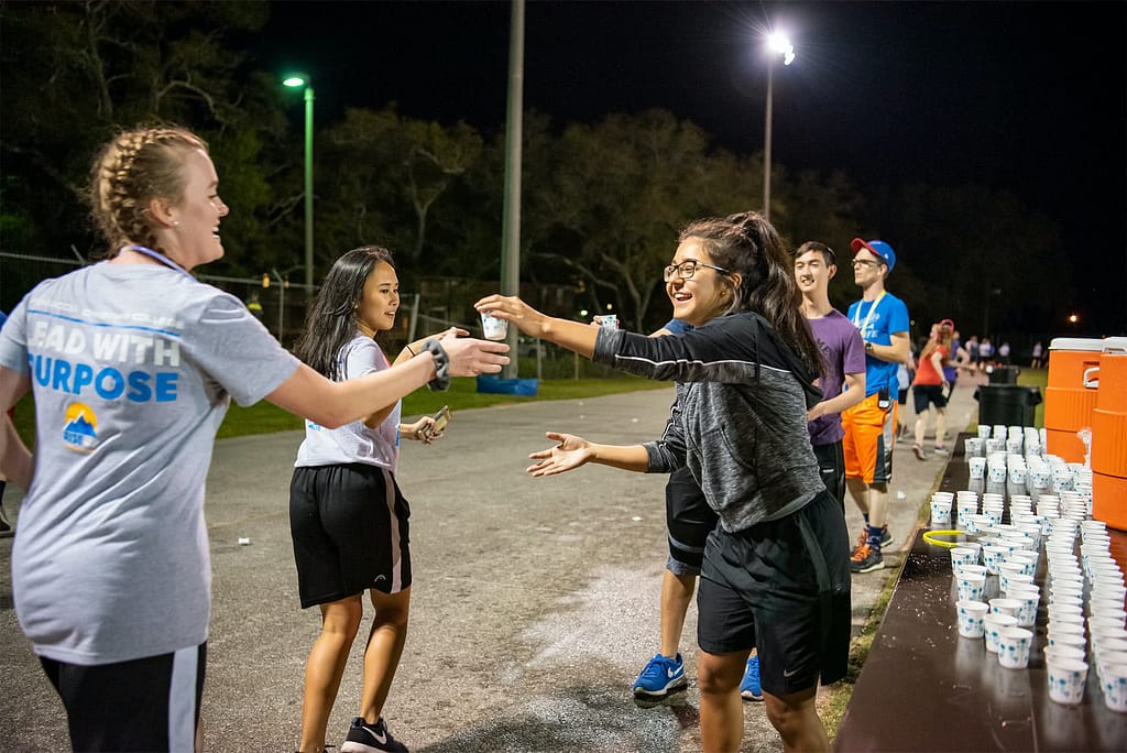 A volunteer passes out water to runners