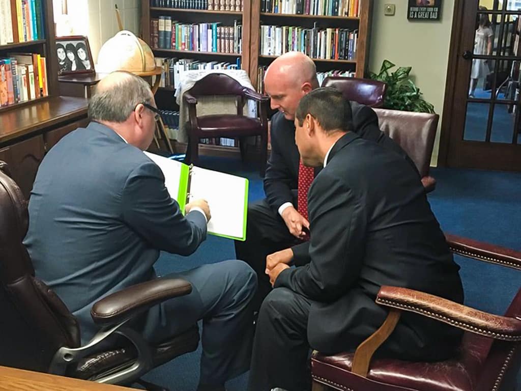 Pastors sitting together and looking at a binder. 