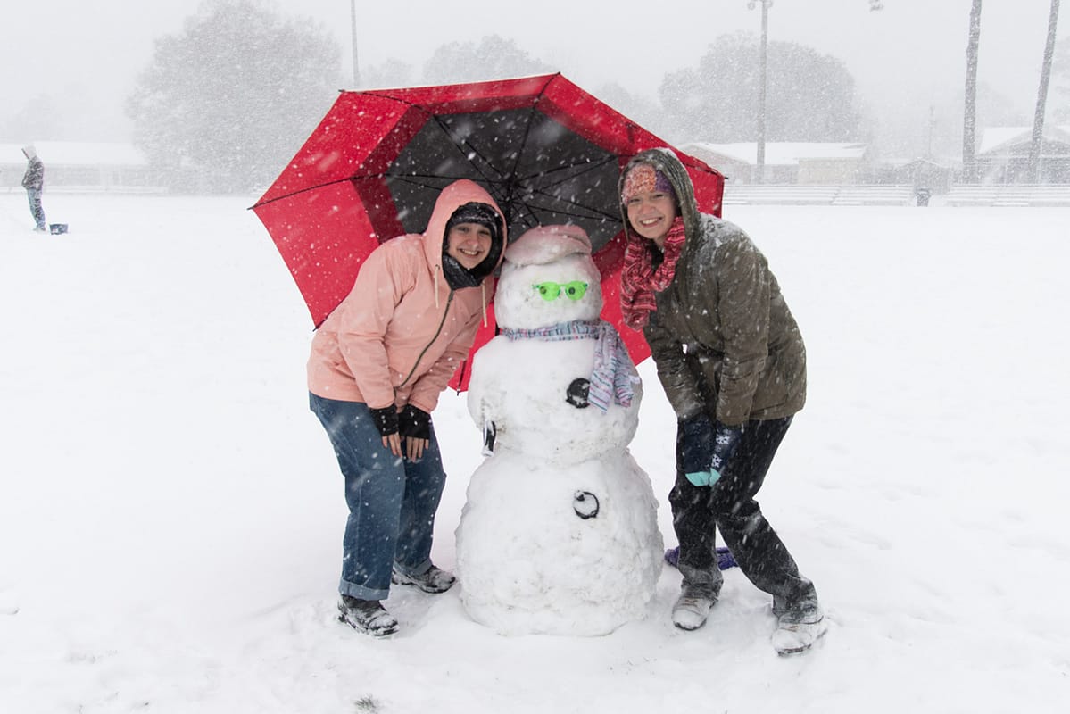 snowman-umbrella PCC girls pose with their snowman and red umbrella.