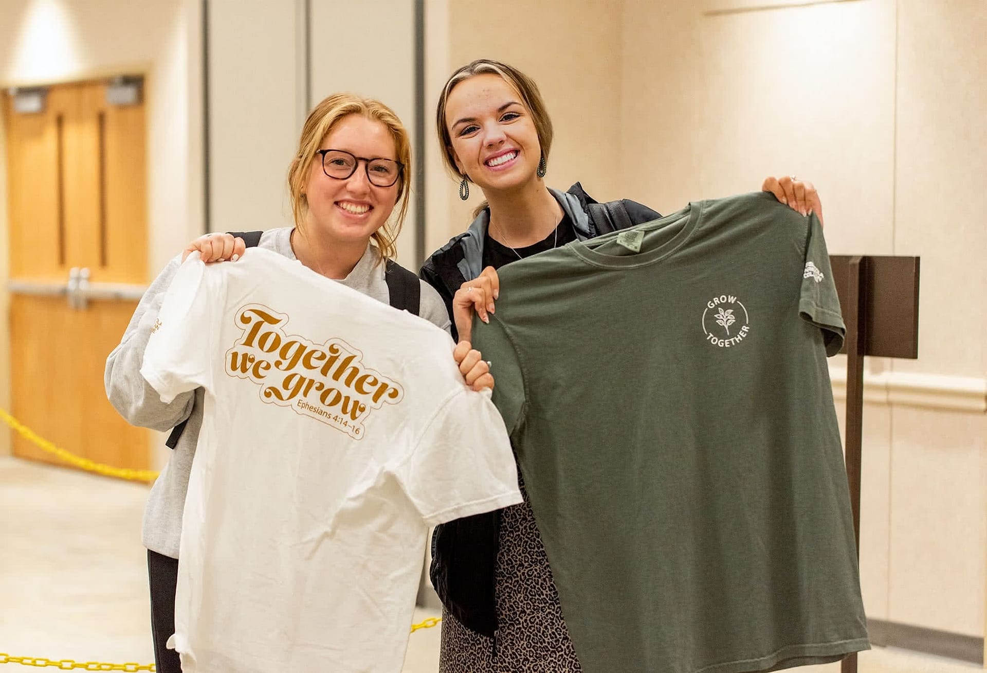 two smiling girl students hold up grow together t-shirts