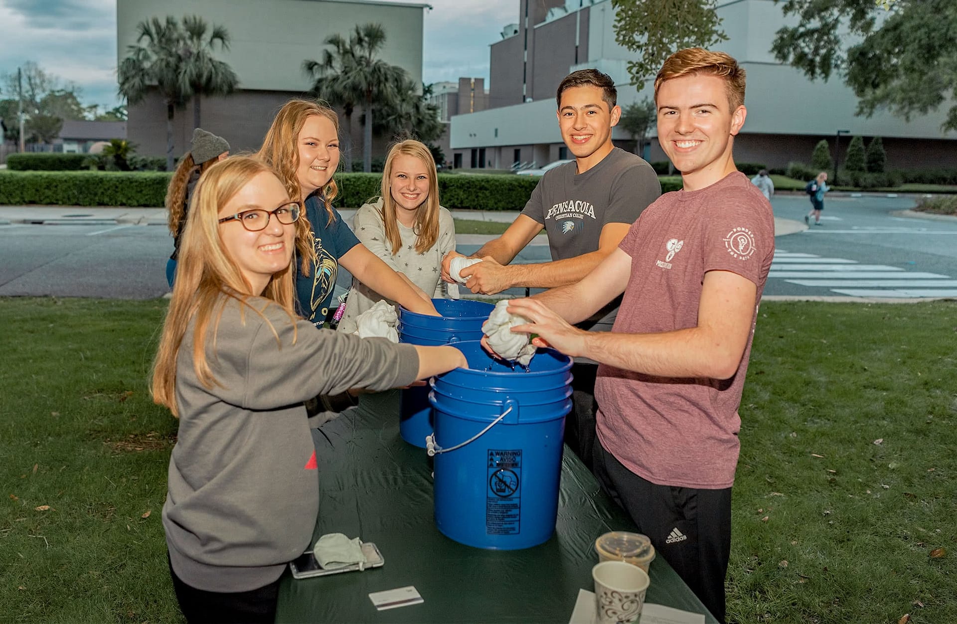 group of five students washing their tie-dye t-shirts