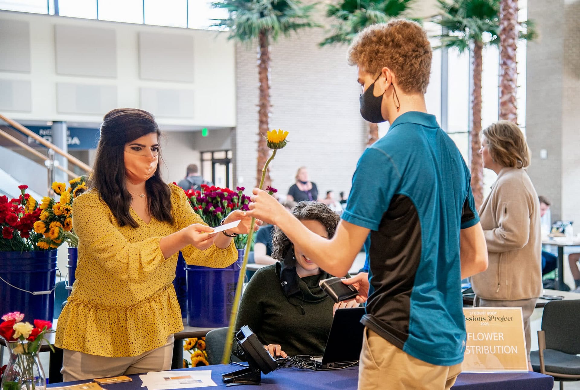 in the commons a female student passes flower to male student