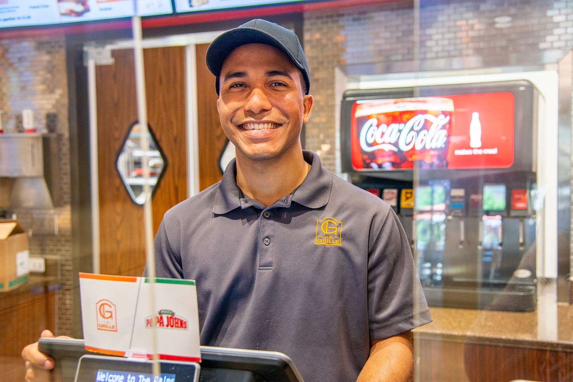 Male student worker at a register working at Palms Grille.