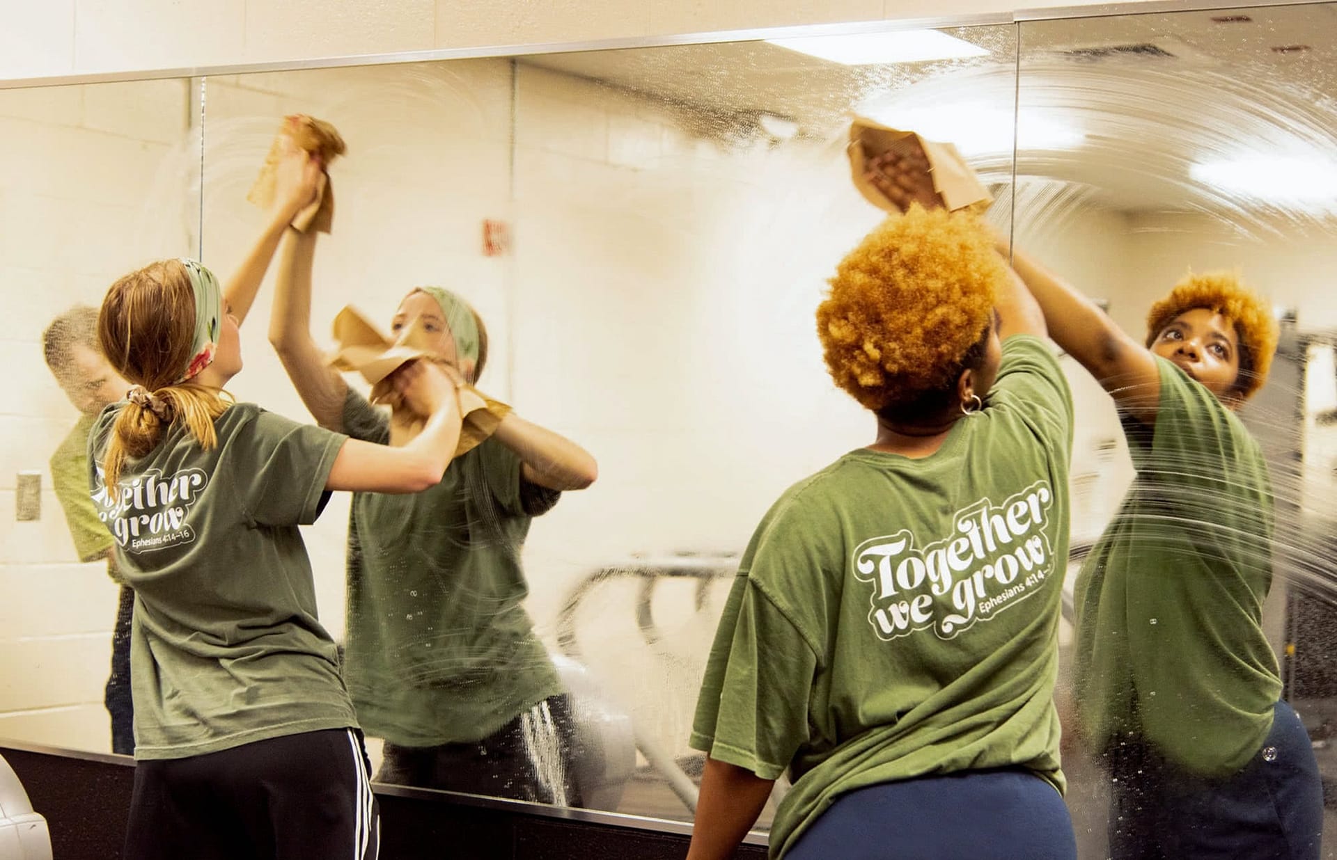 Two girl students clean mirrors