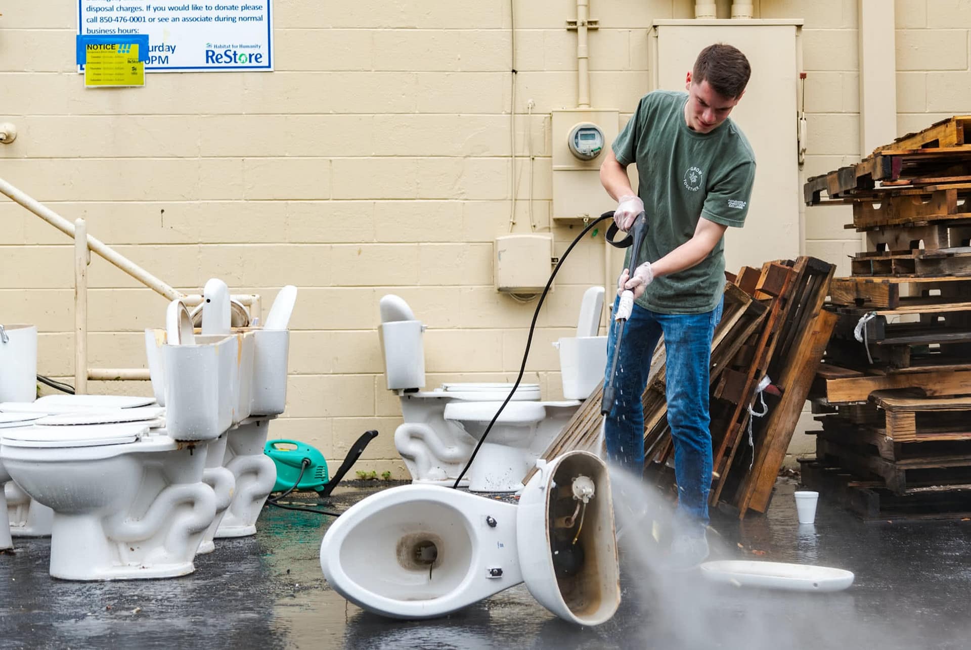 Male student pressure washes toilets