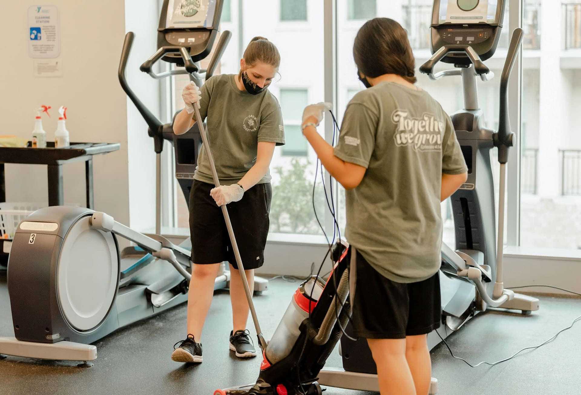 Two female students clean gym floor during serve pensacola