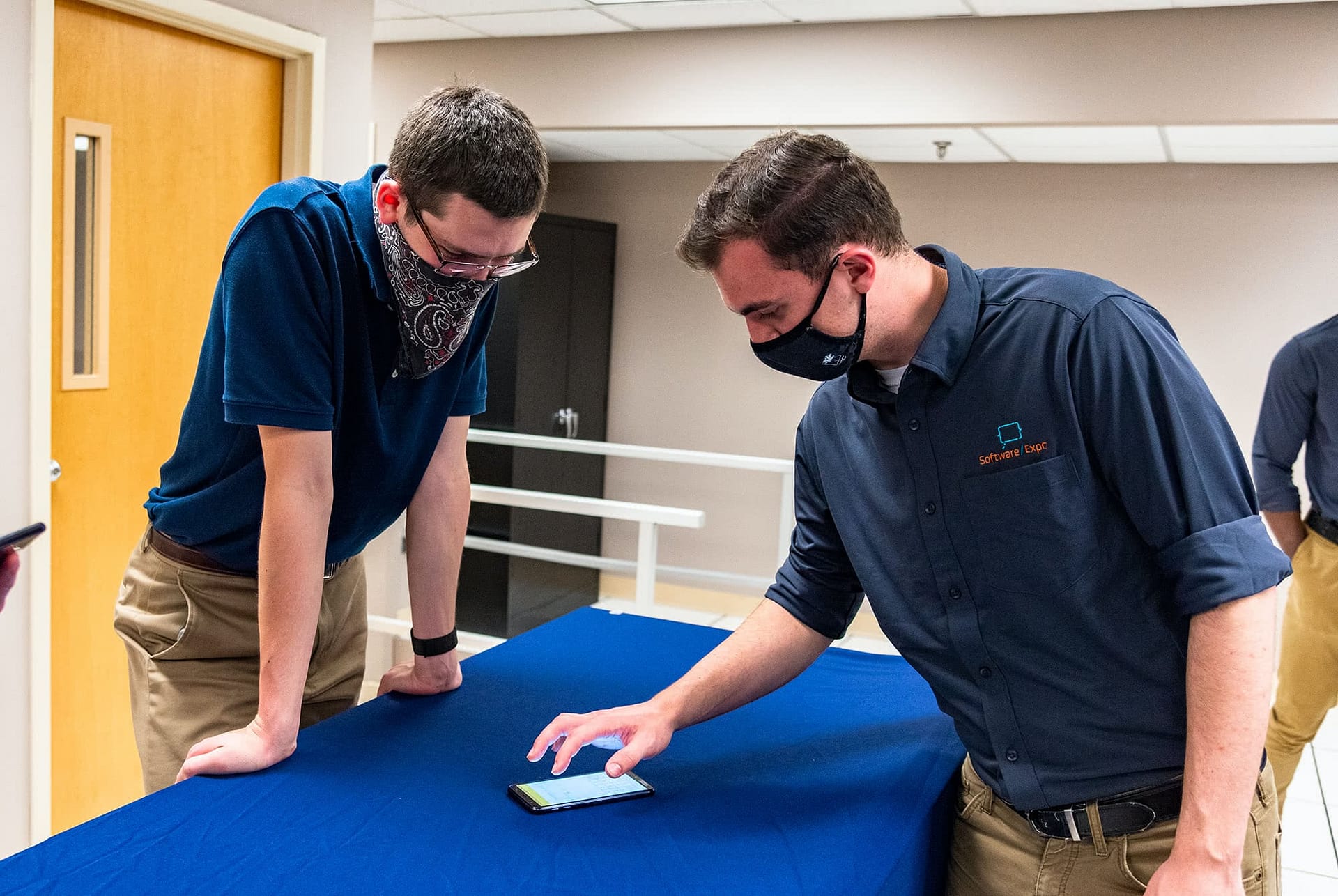 Man showing a student information on a phone at the Software Expo.
