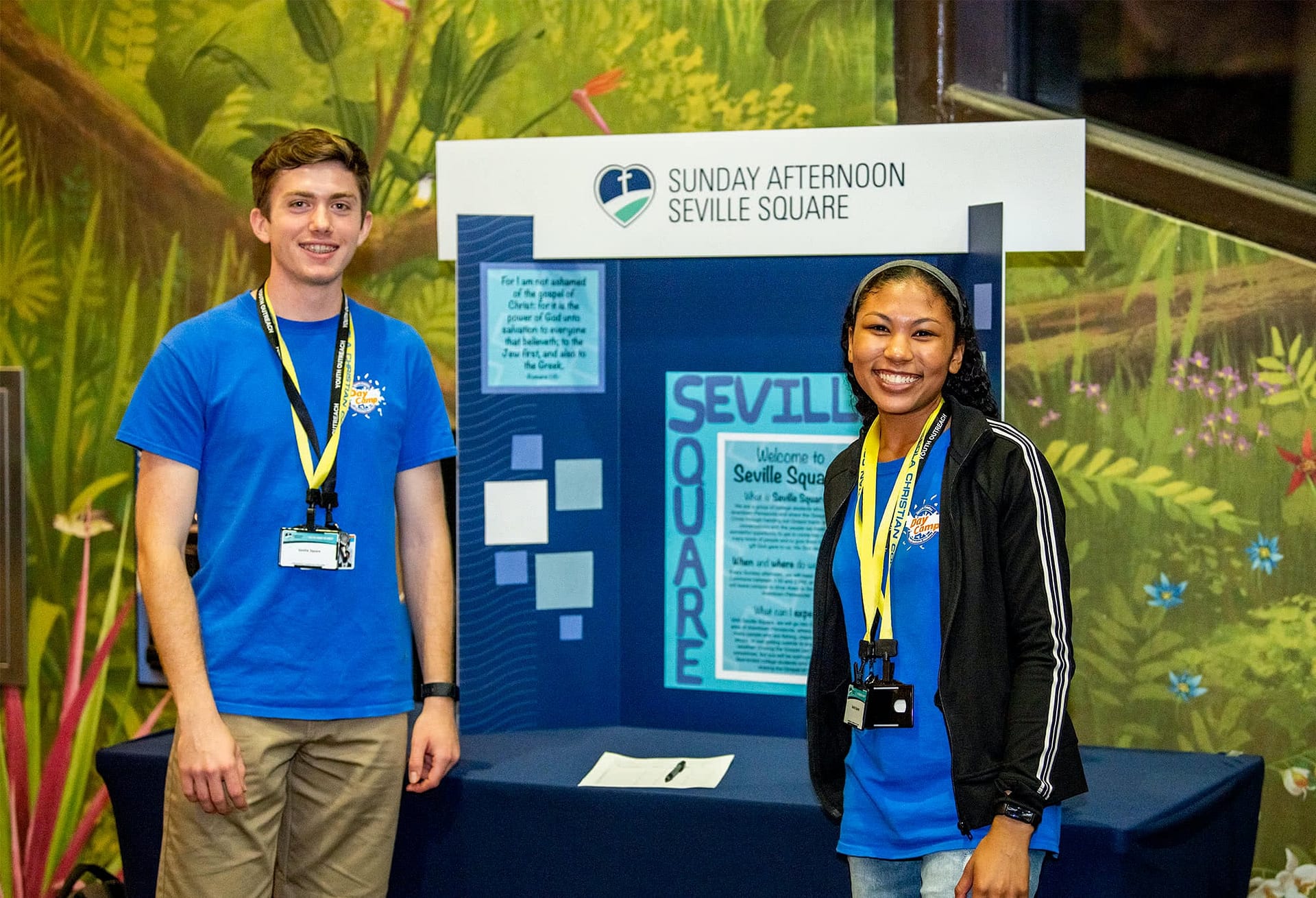Two student Summer Day Camp workers standing in front of a display table.