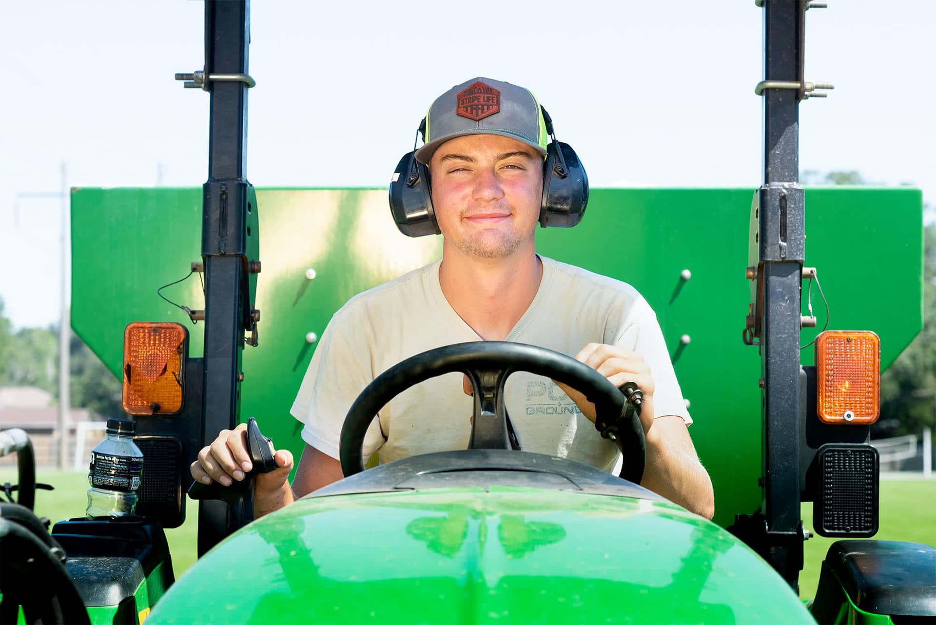 Male student grounds worker driving a tractor.