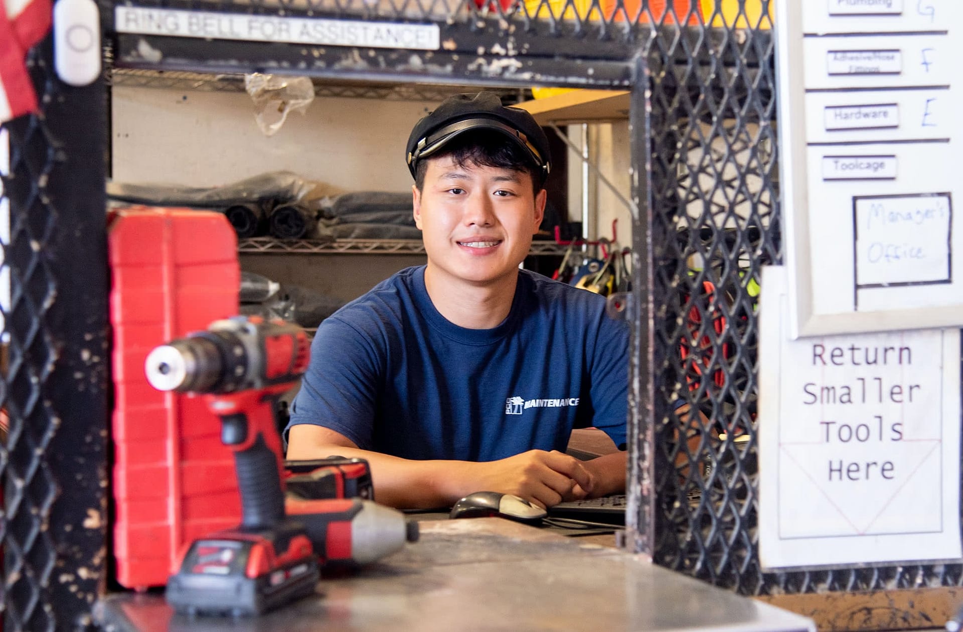 Male student maintenance worker standing at a desk.