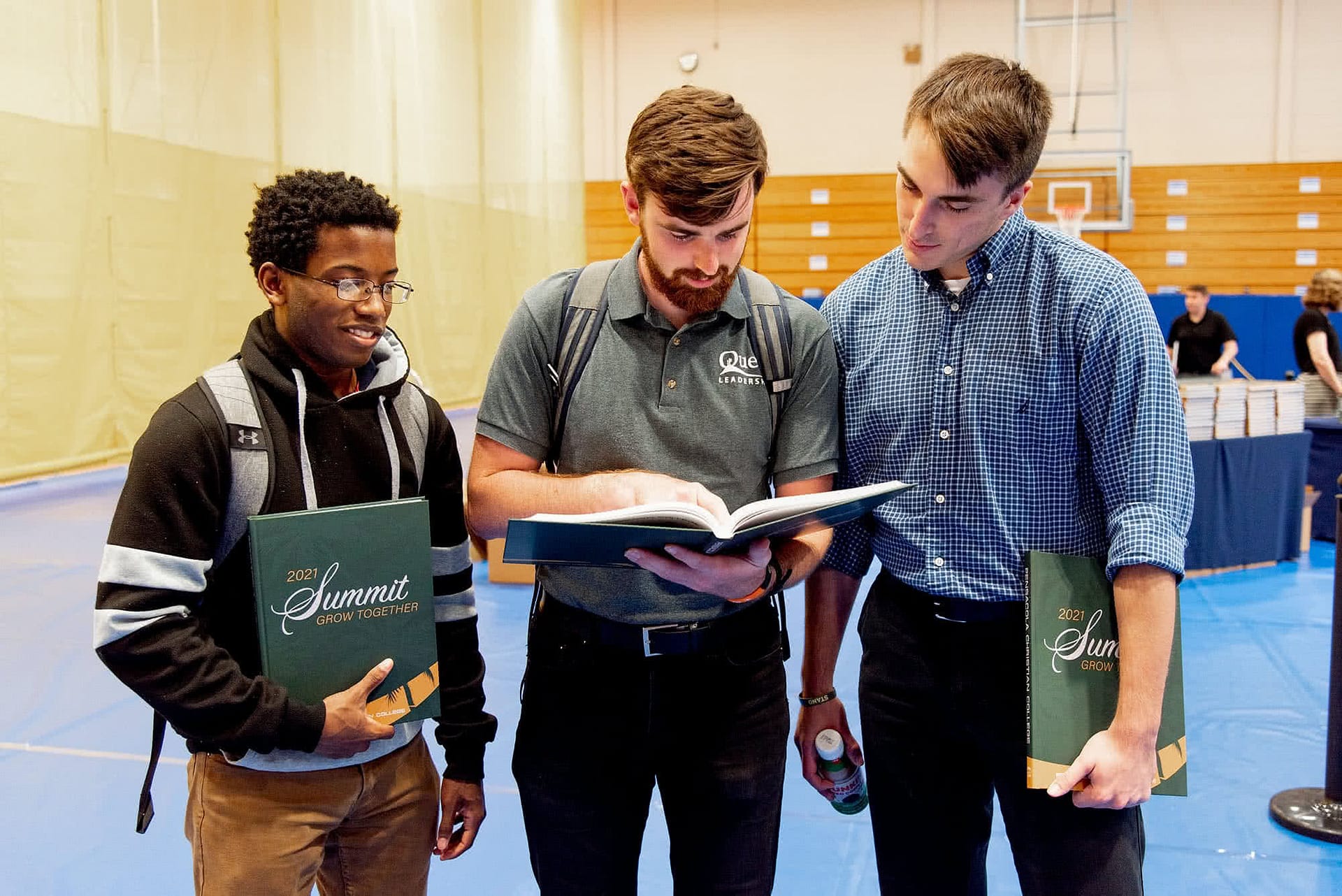 Three male students gathered together looking at photos in a Summit yearbook.