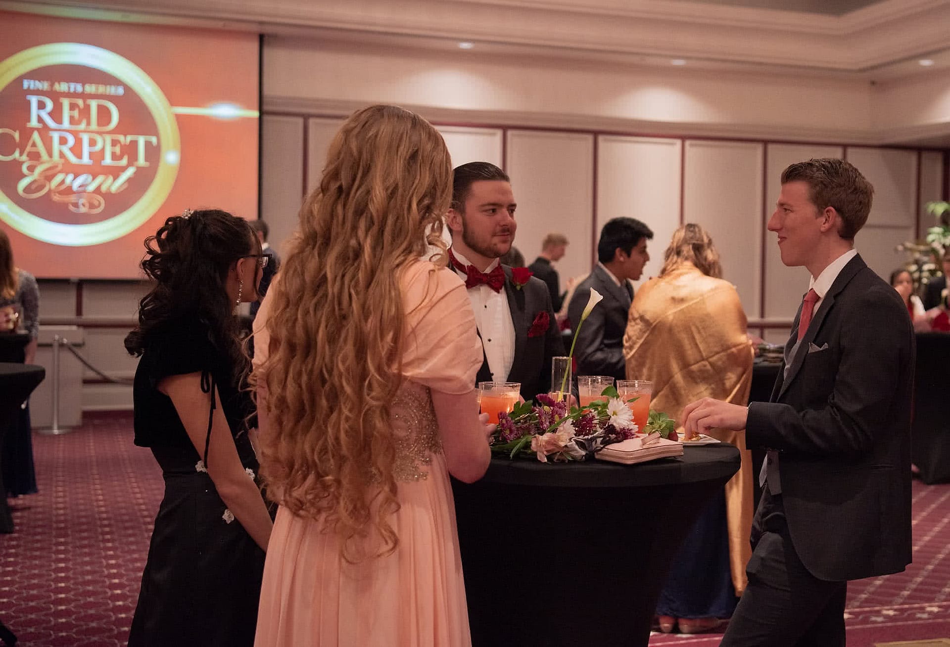 Four students standing around a table and smiling. 