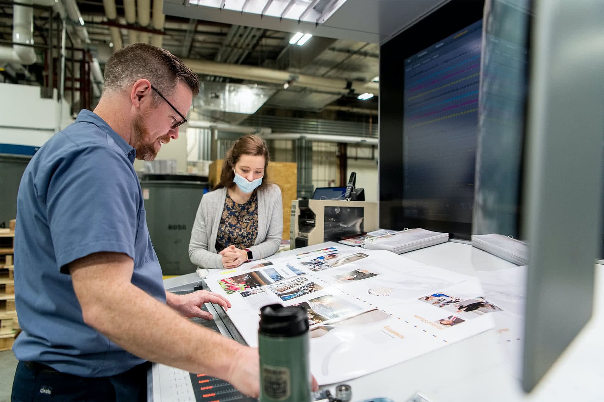 Male and female staff observing paper with photos. 