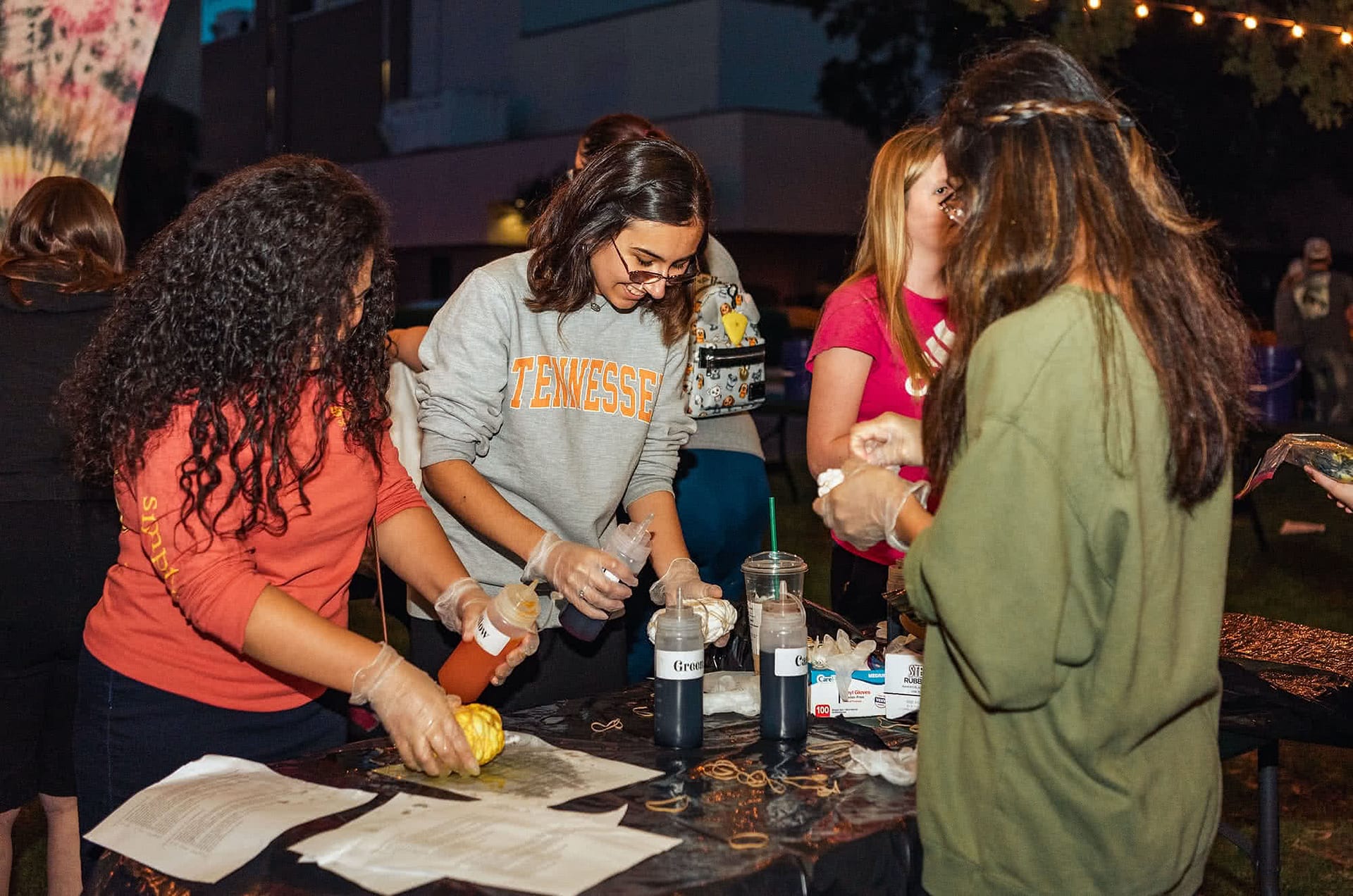 Female students standing at a table with bottles of tie dye.