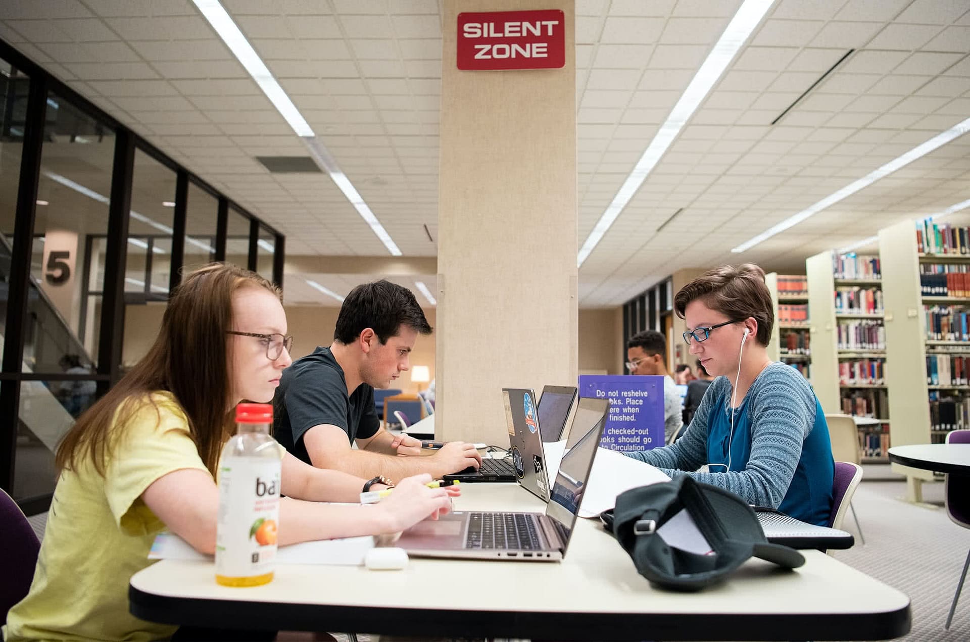 A trio of friends study in the library