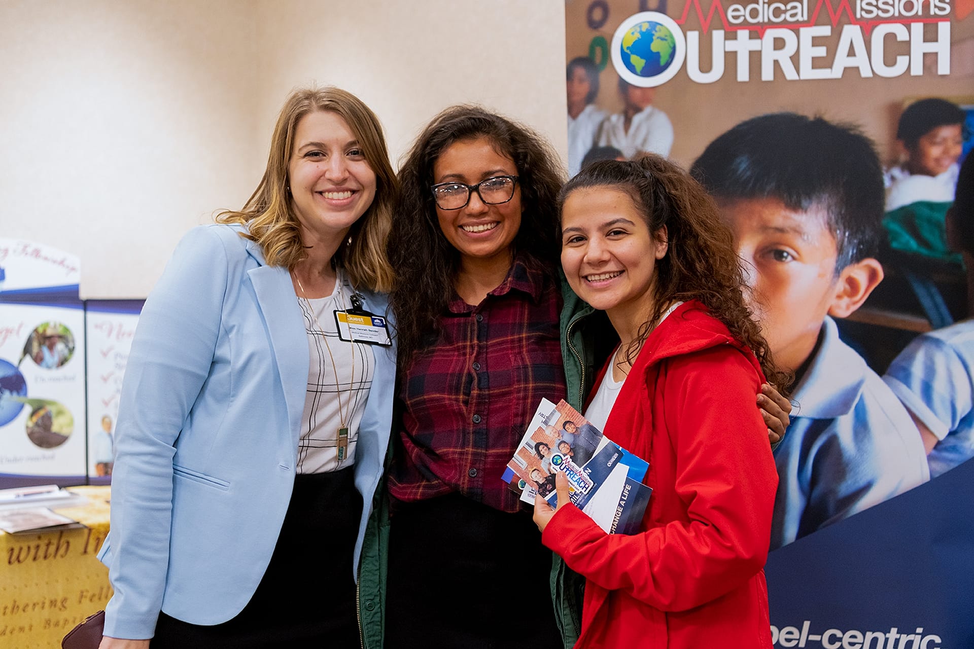 Students pose with missionary representative at their booth.