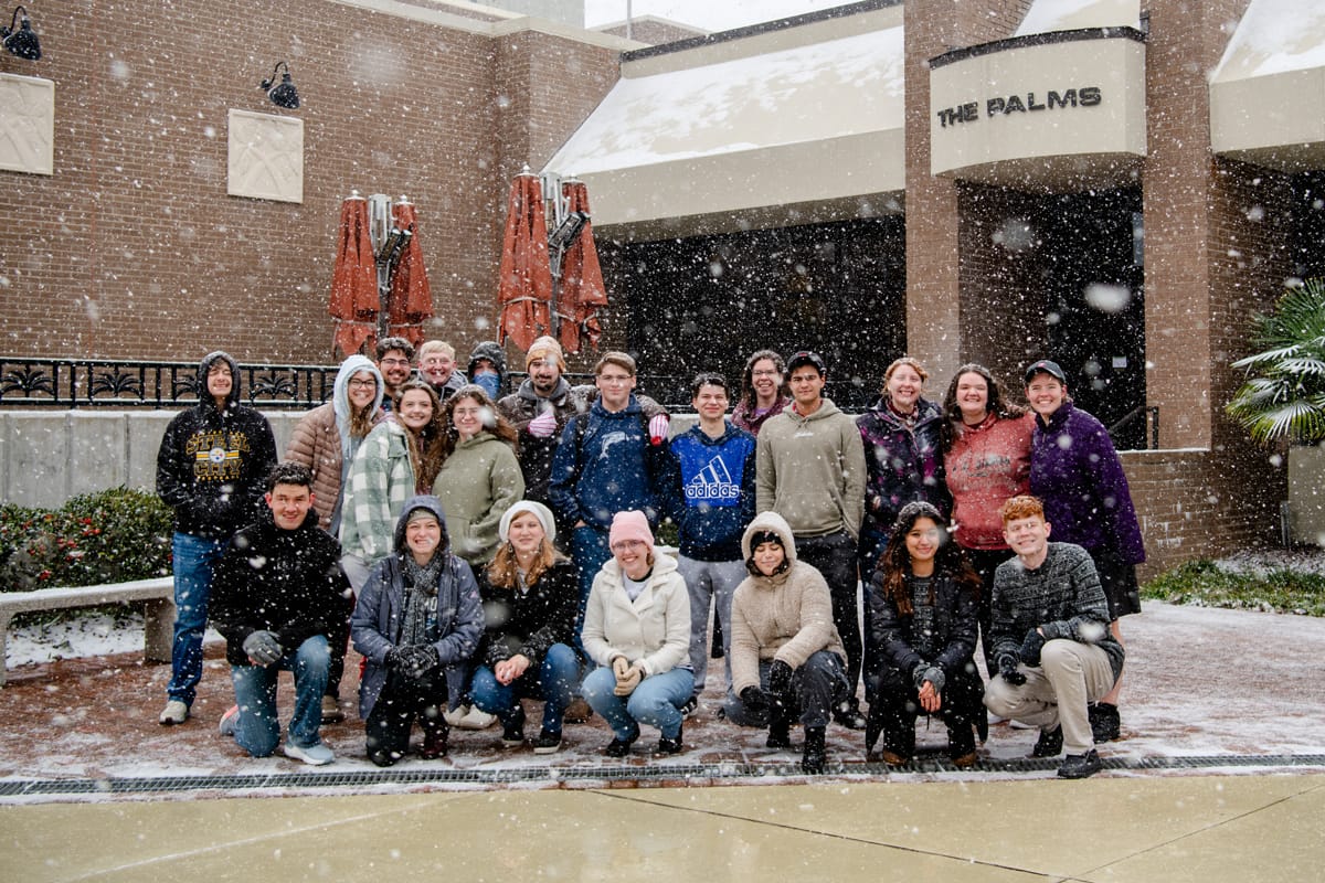 group-palms-snowing PCC Students pose in the snow in front of the Palms.