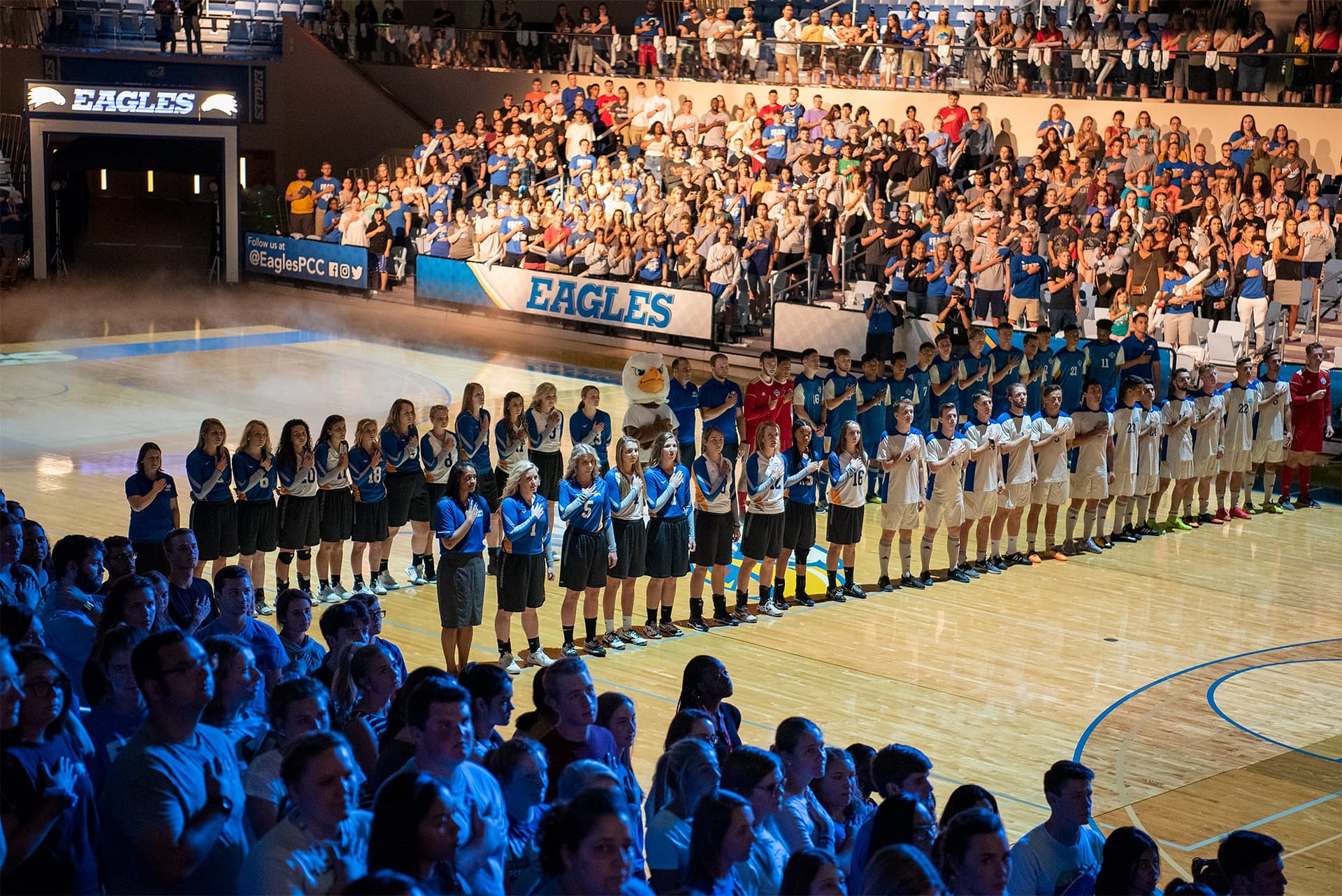 The volleyball and soccer teams, Eagor, and student body sing the national anthem