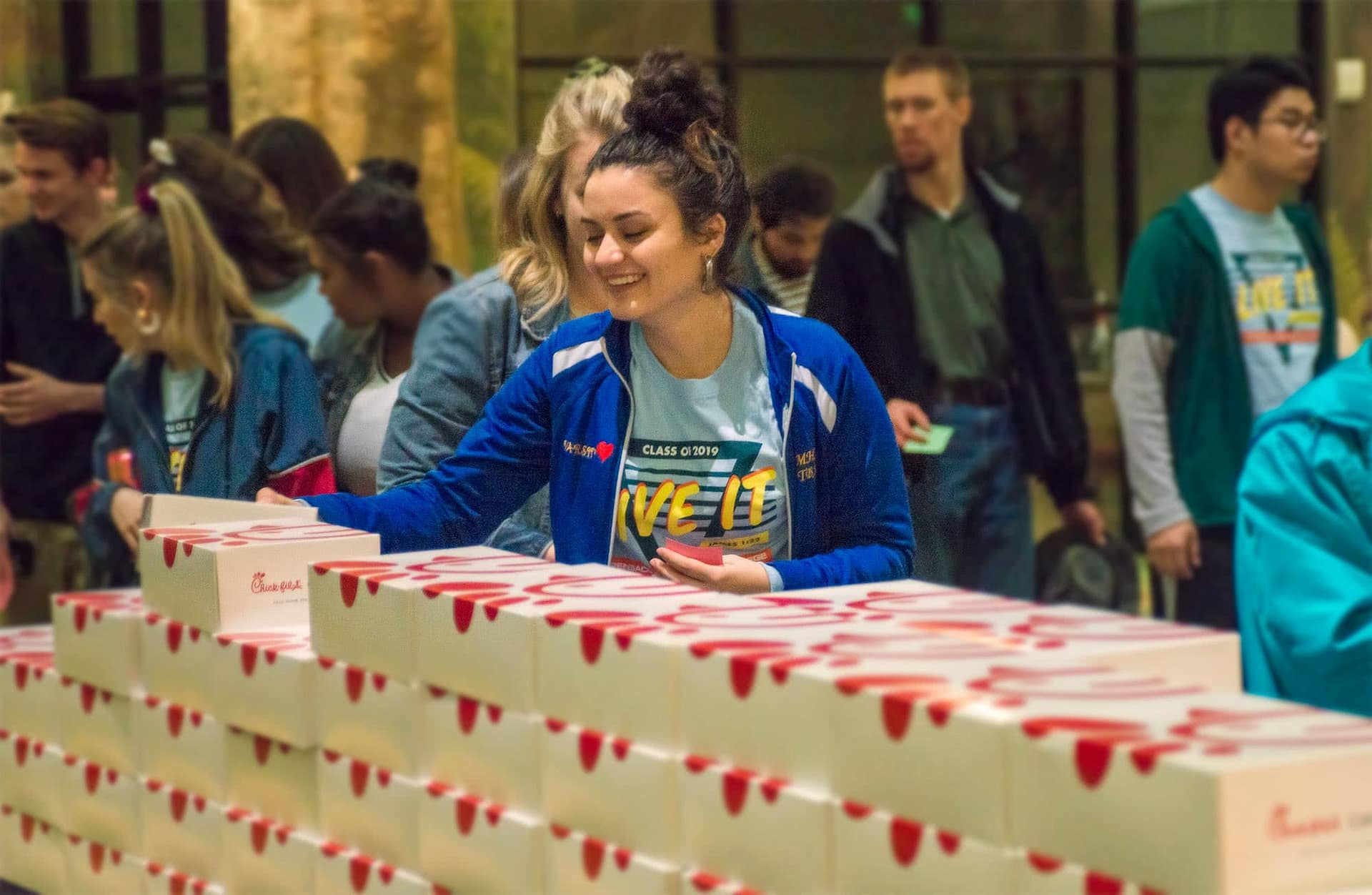 Female students lining up for Chick-fil-A meal boxes at their senior class party..
