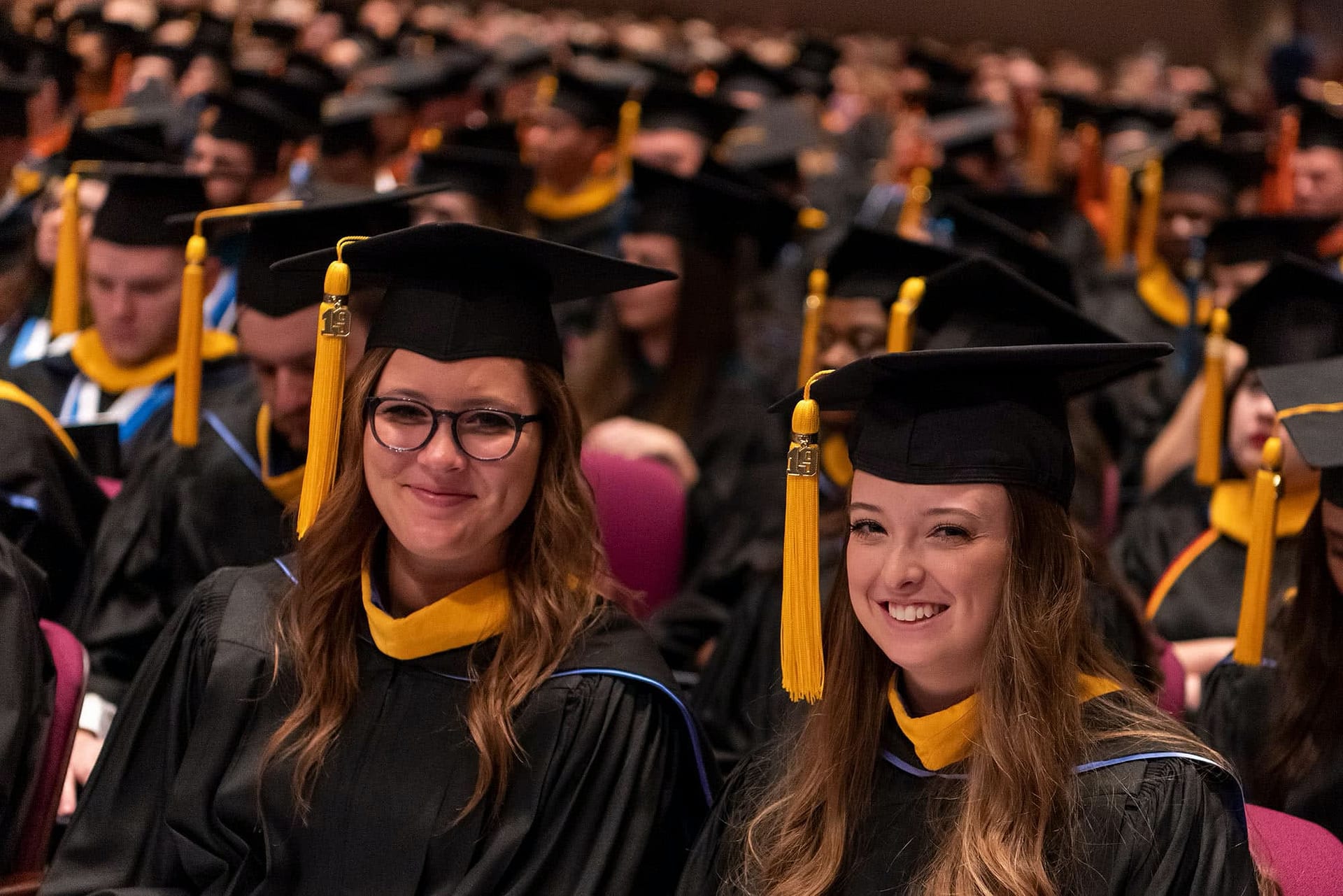 Two graduates smile for a picture during graduation