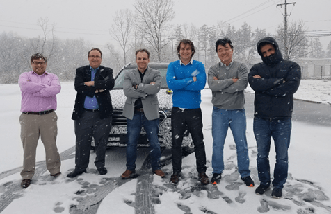 Men standing in snow crossing their arms over their chest.