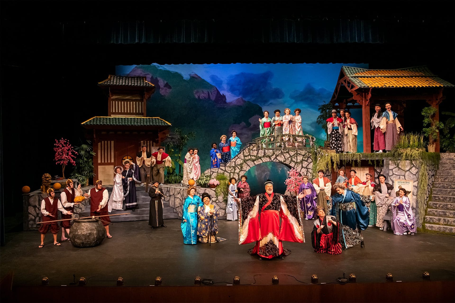 Men and women in Japanese costumes standing around a stage set.