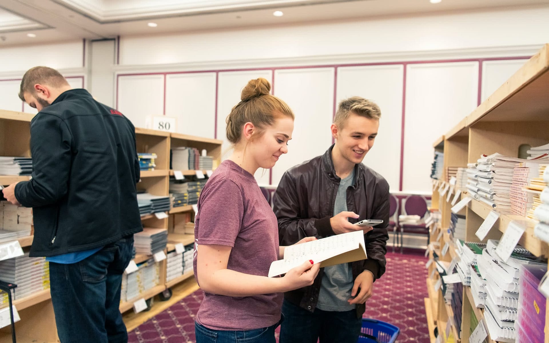 Male and female student looking at books at the book sale.