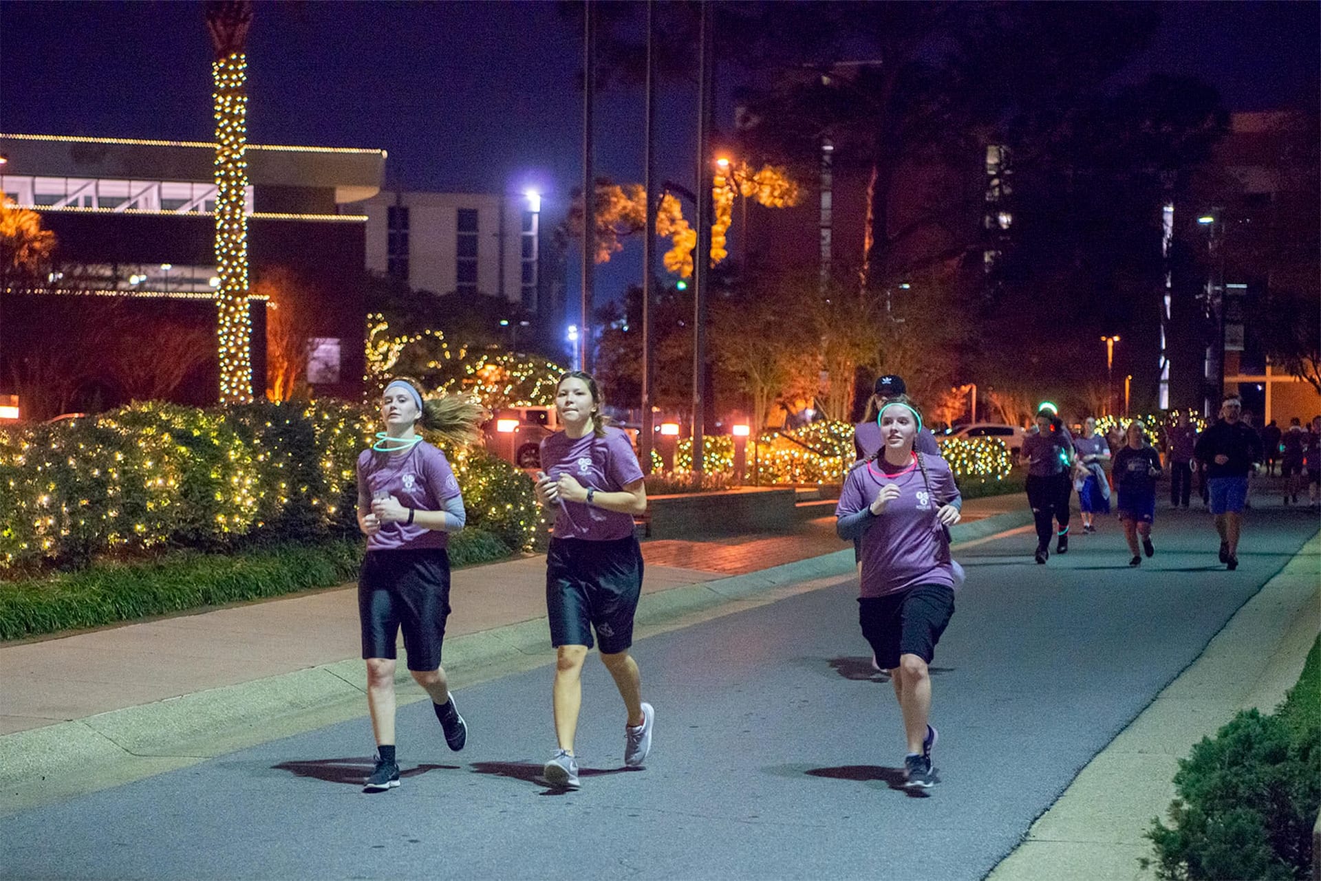 Three female students run in front of the administration building