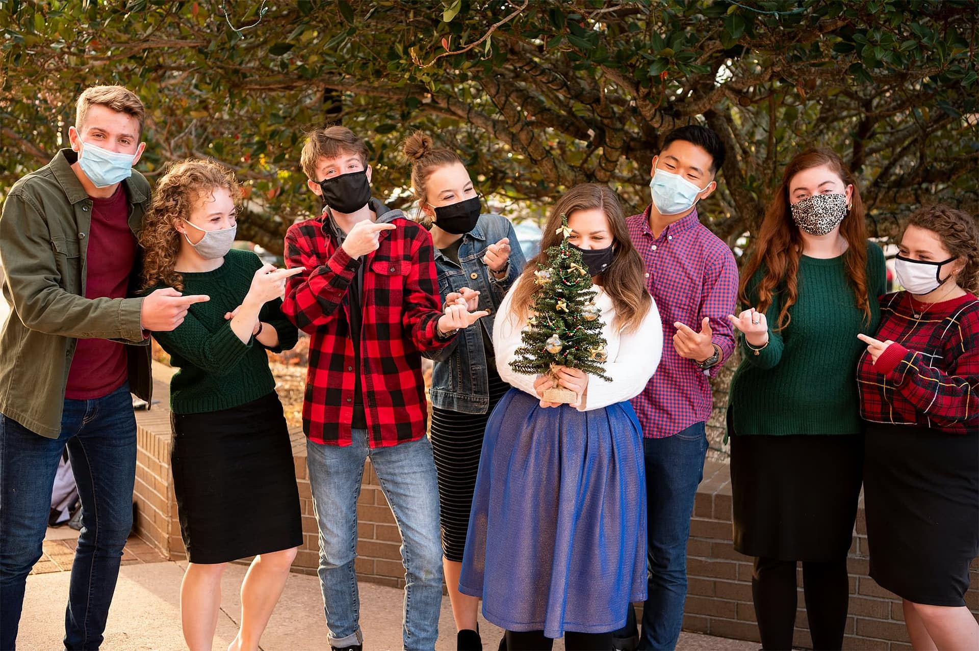 A group of students decorating a small Christmas tree