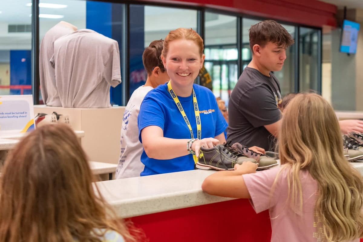 Sports Center Day Camp worker gives out bowling shoes