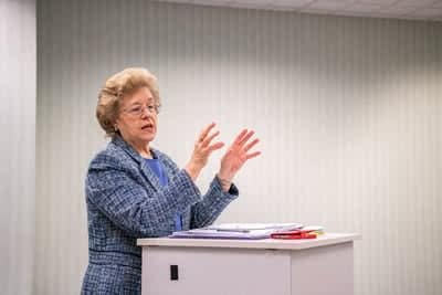 Dr. Monk standing at a podium and holding up her hands as she talks. 