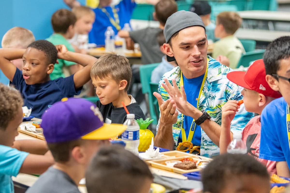 scdc-wk2-meal Sports Center Day Camp team leader talks with campers during their meal time