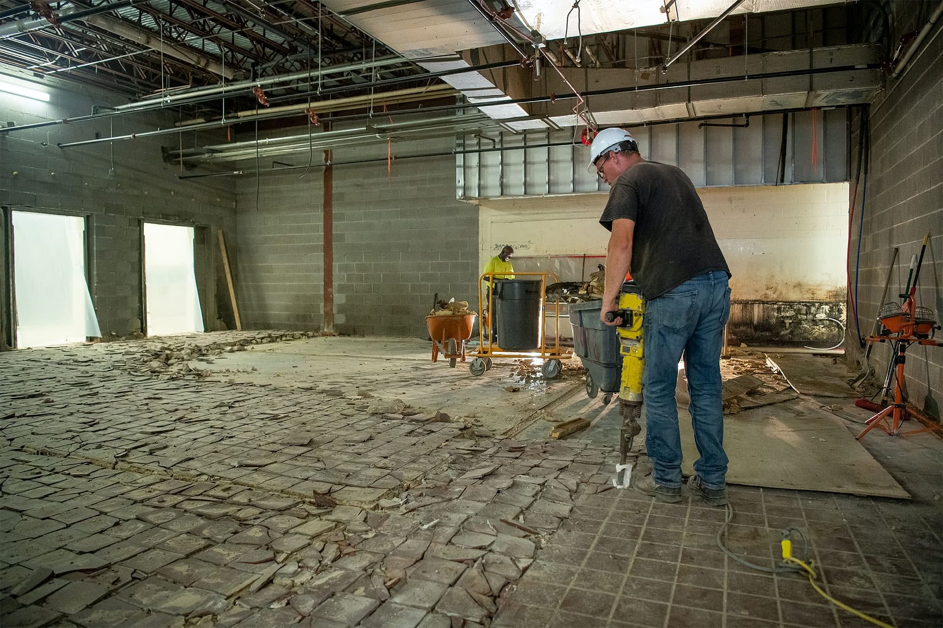 Construction worker using a jackhammer to break up tile.