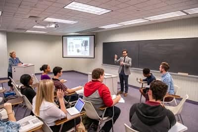 Male student standing in front of a class and giving a speech.