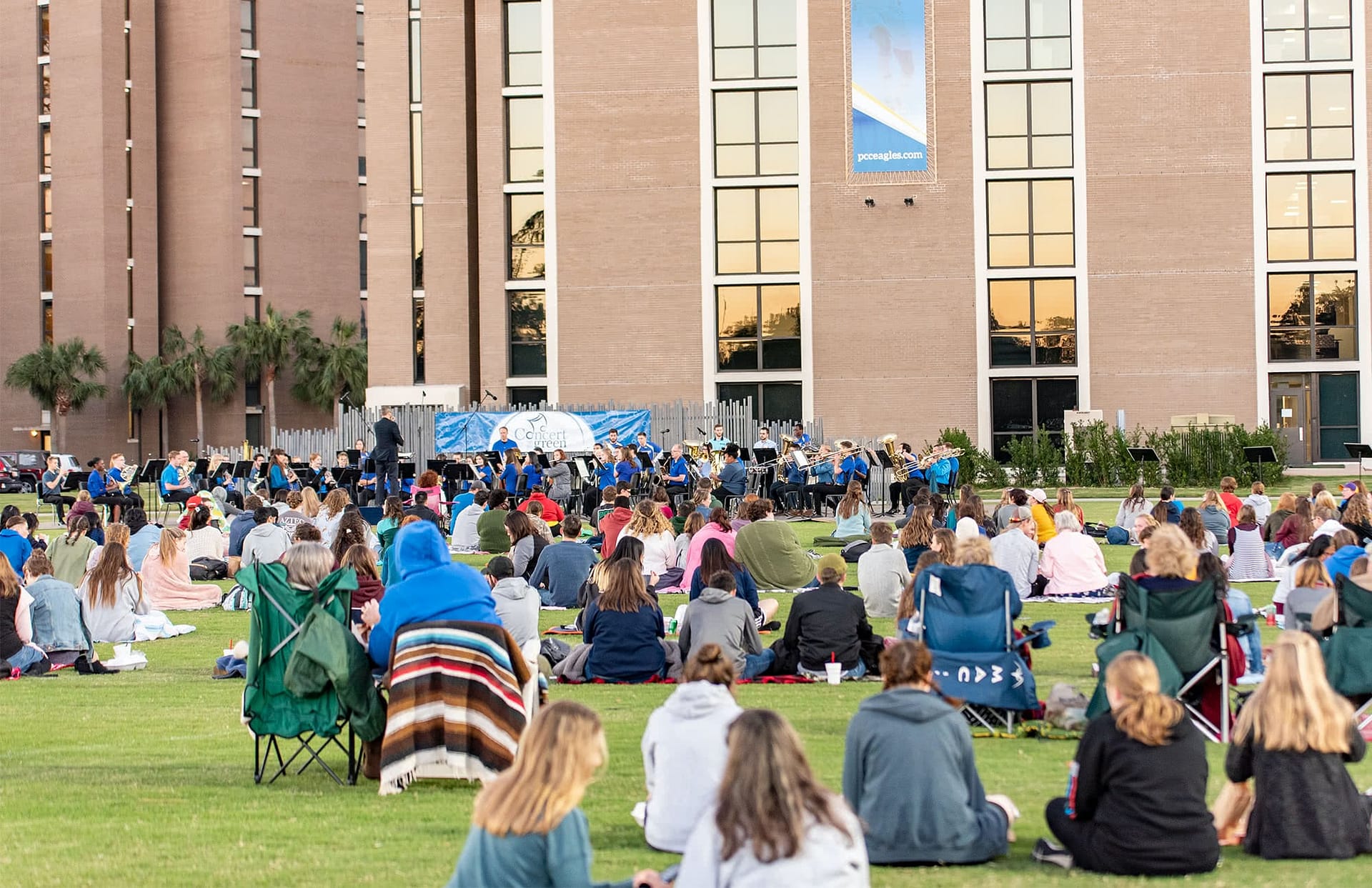Students sitting on Eagle Field to watch the Symphonic Band perform.