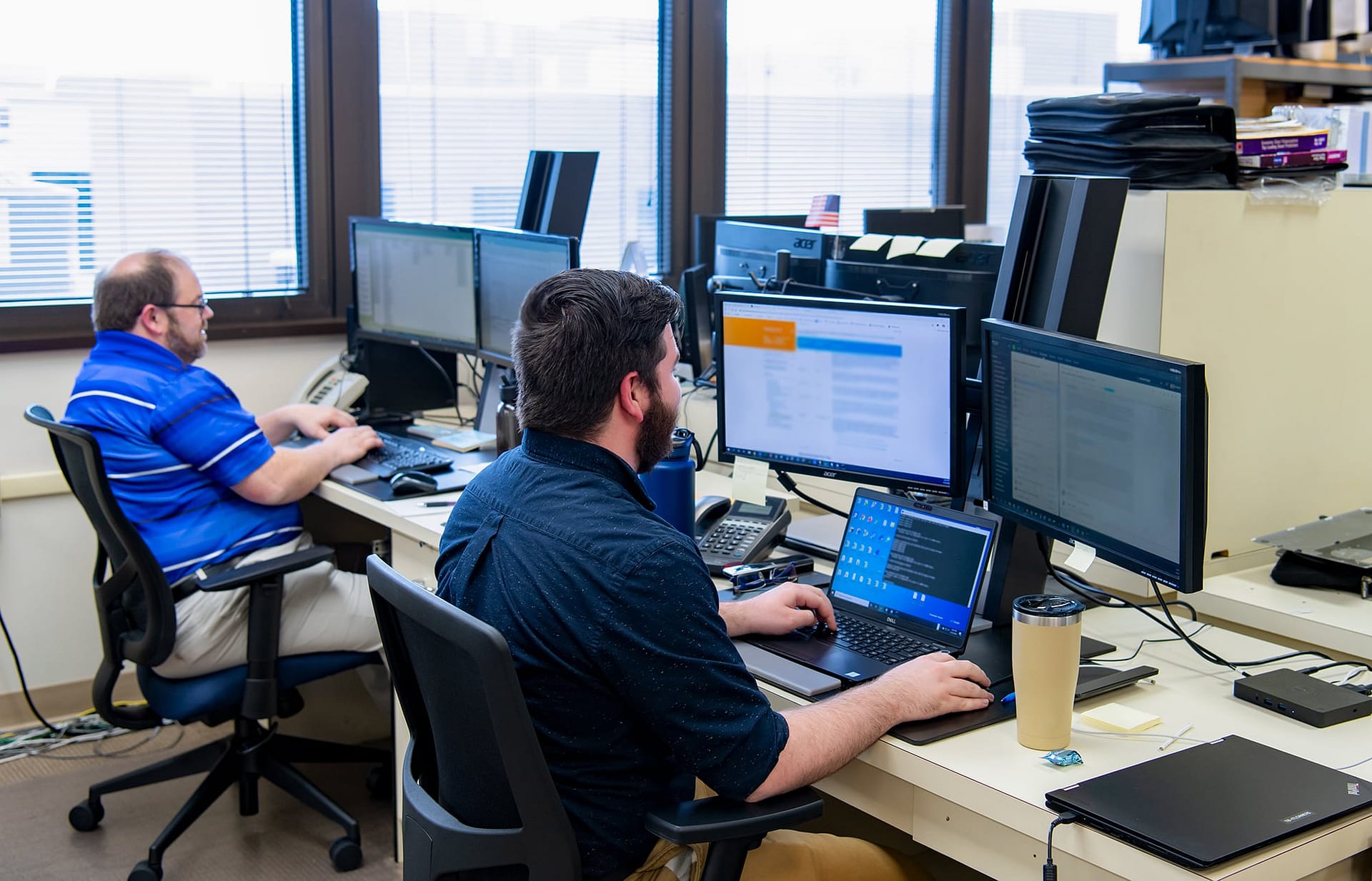 Two IT staff members at their desks.