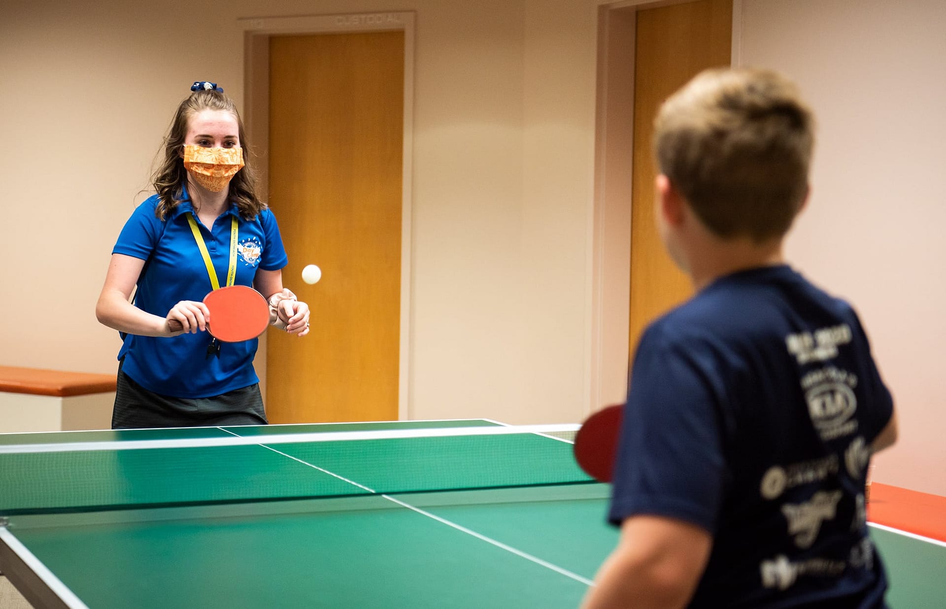 Sports Center Day Camp counselor playing ping pong with a camper. 