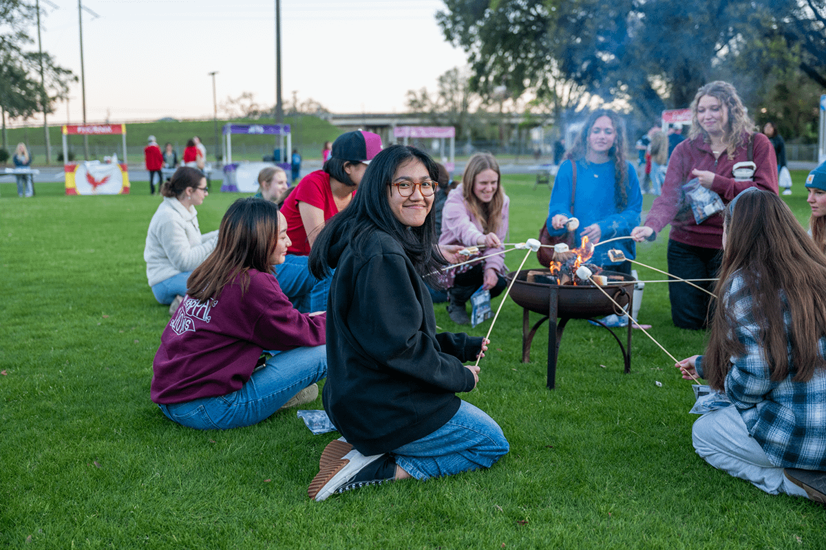 Friends cook s'mores around a fire pit
