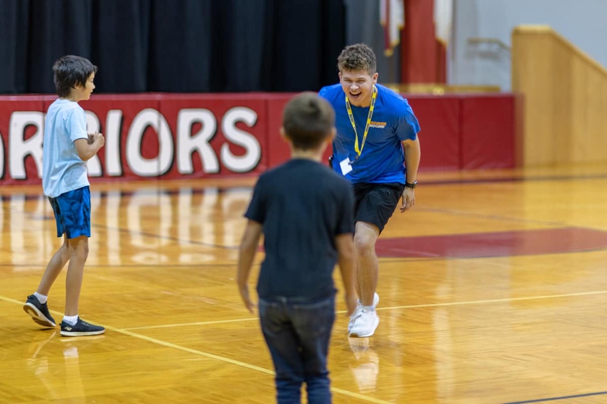 ddc-academic-activity-gym Discover Day Camp team leader plays with campers in the gym