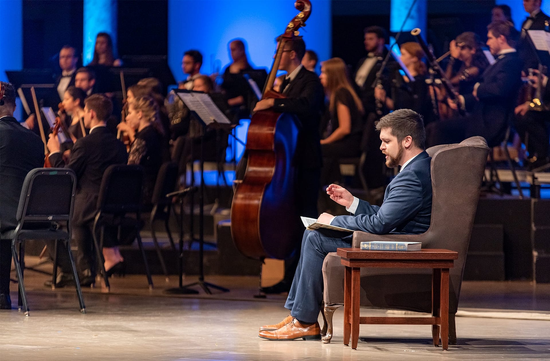 Josh Hutt sitting and narrating on Crowne Centre stage.