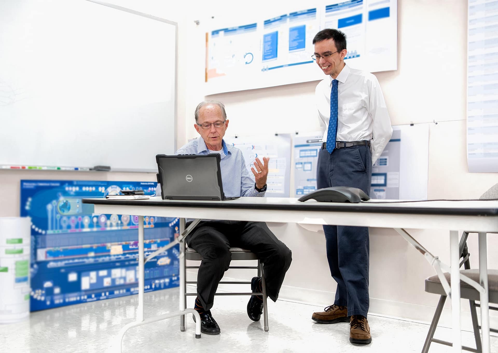 Two members of IT staff look at laptop.
