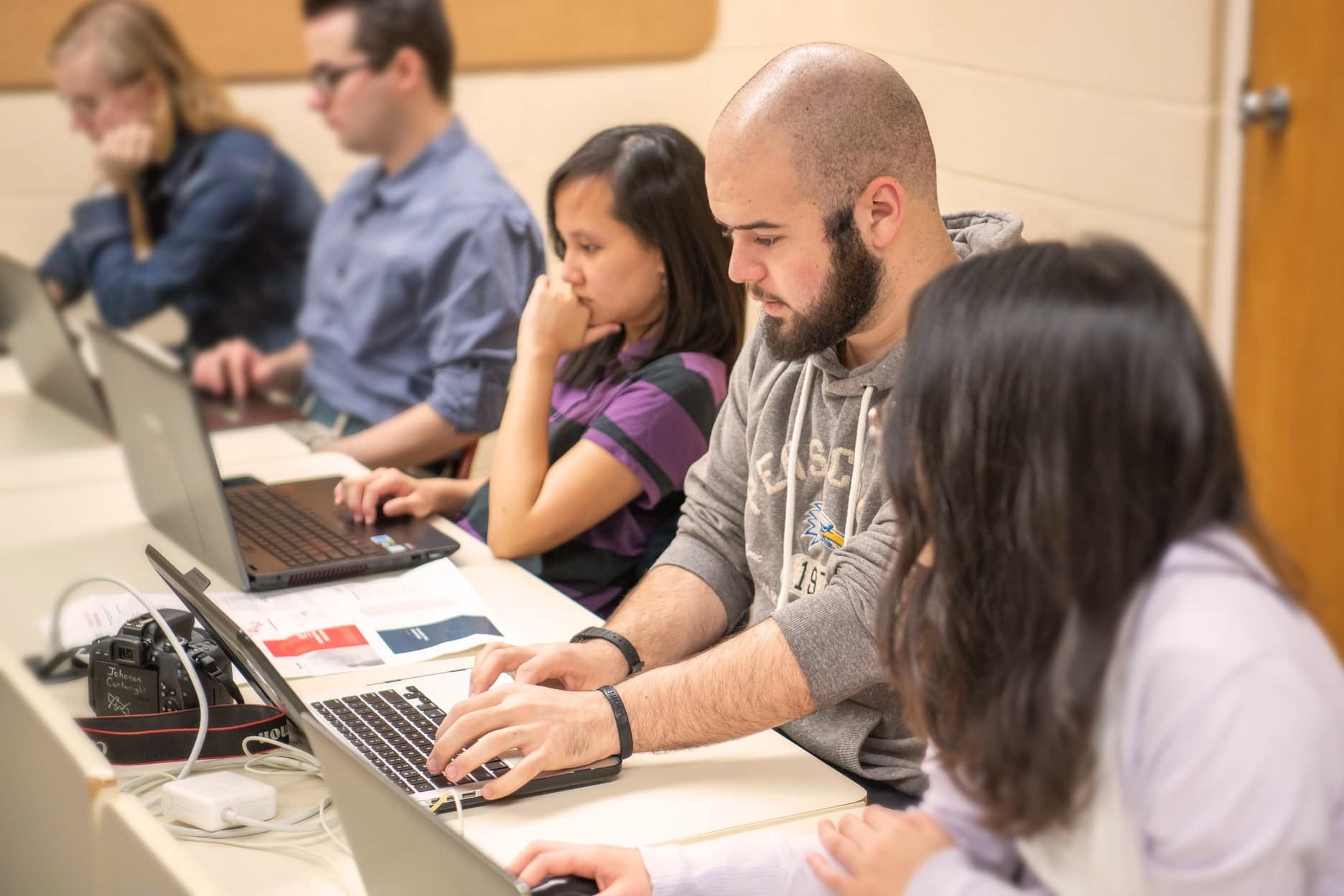 Students sitting at desks and working at their laptops.