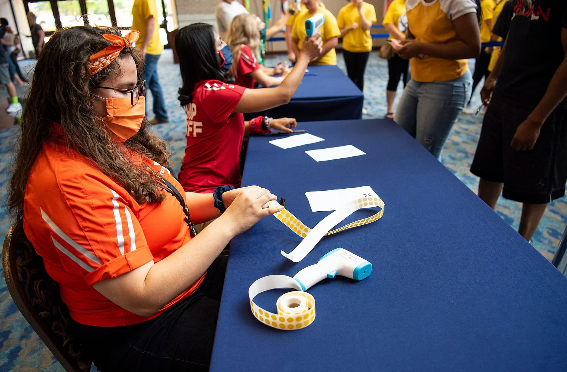 Teen Extreme camp counselor giving out orange stickers at camp check in. 
