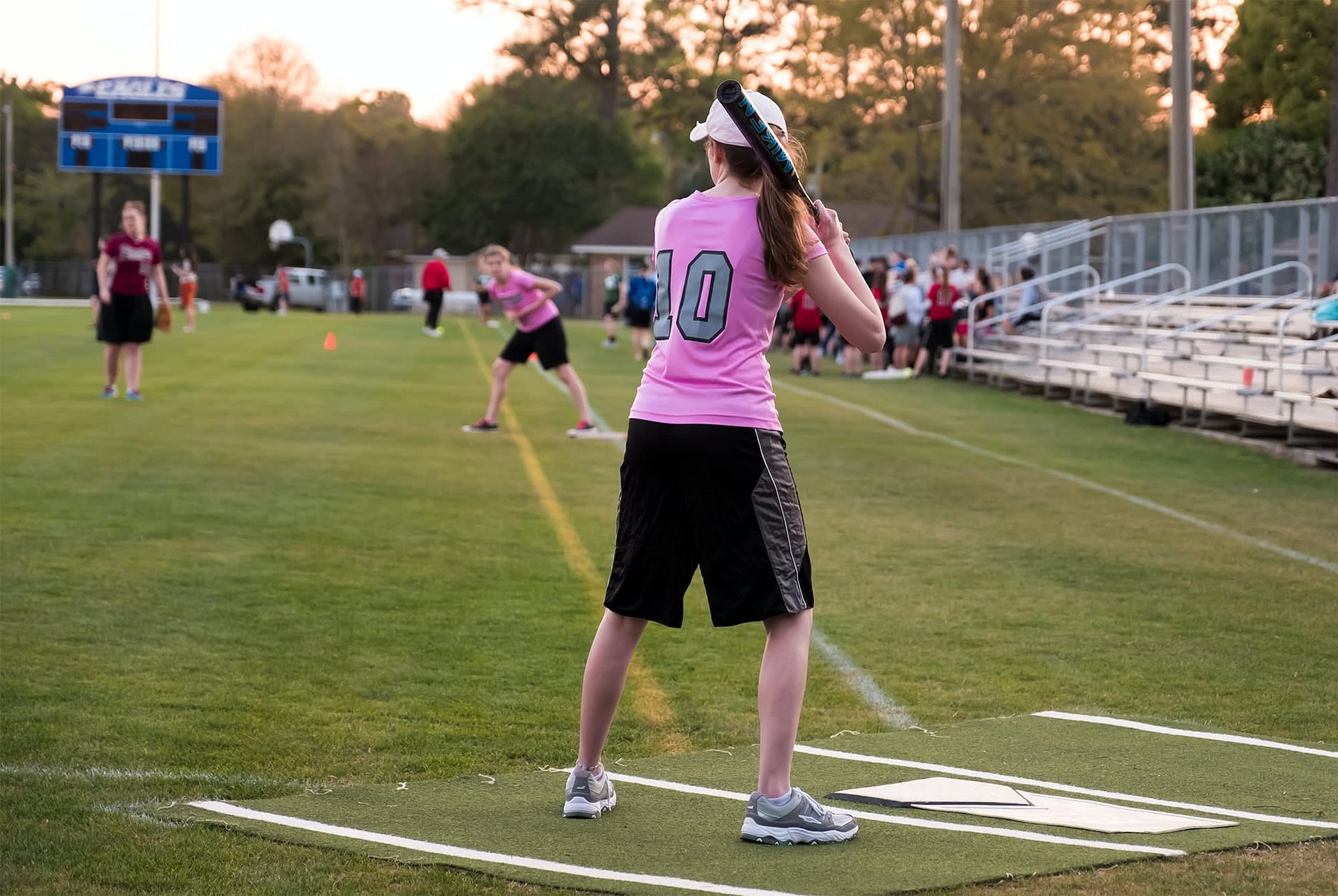 Women's collegian softball player holding a bat. 