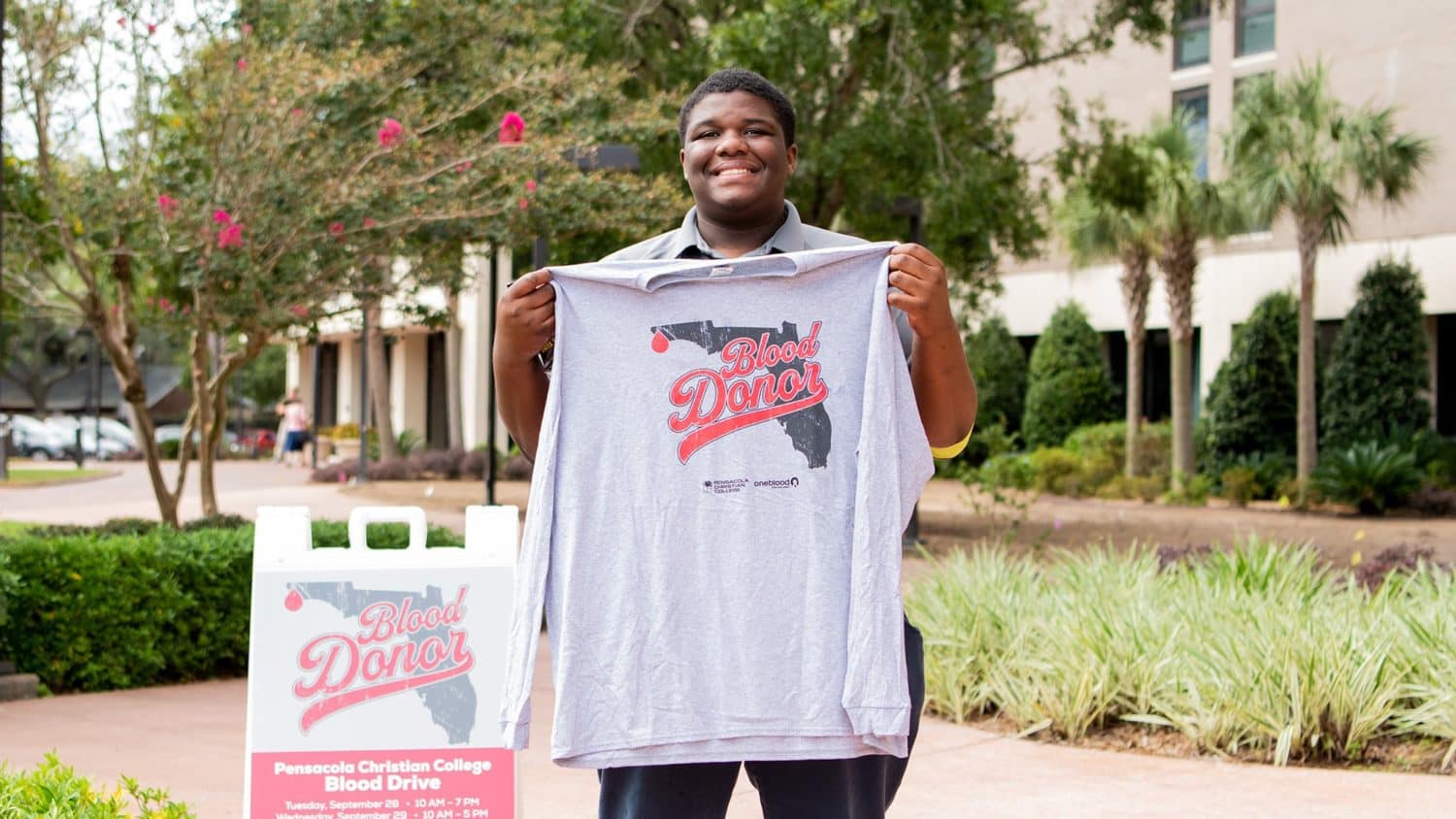male-student-holding-up-shirt Male student holding up t-shirt